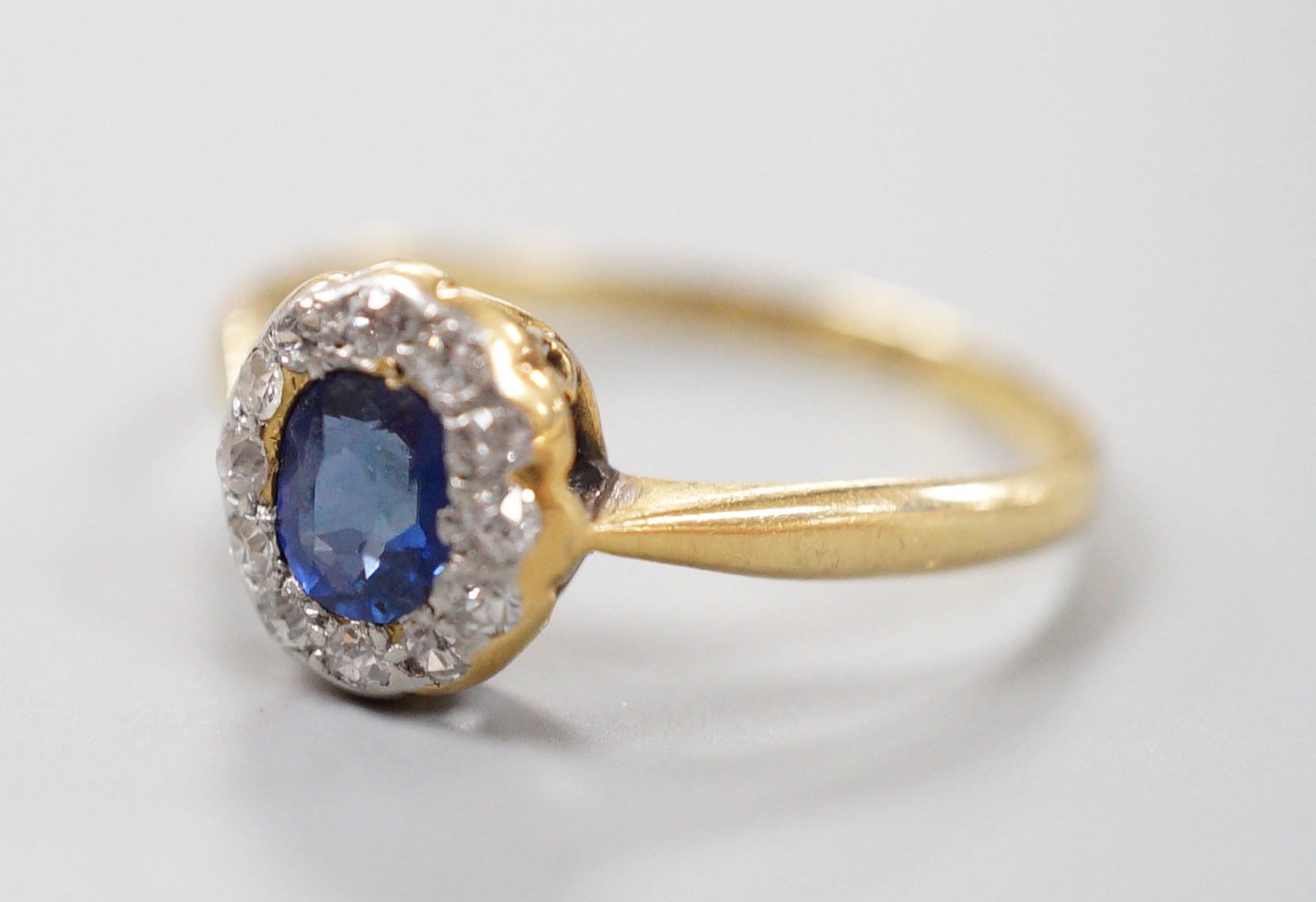 An 18ct, sapphire and diamond set oval cluster ring, size M, gross weight 1.7 grams.